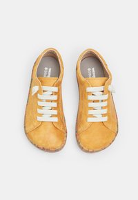 Adidași din suede galben cu șireturi albe, vârf rotunjit și talpă speckled multicolor. Interiorul are un călcâi cu perna pentru confort.