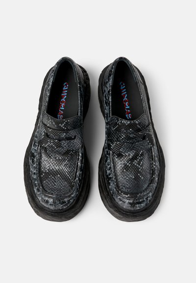 Black and gray snakeskin-patterned shoes with a thick black rubber sole and a rounded toe. Features a textured surface and slip-on design.