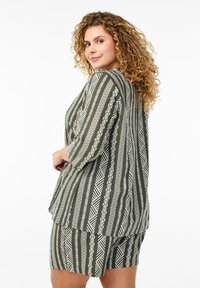 Completo verde oliva con un motivo geometrico bianco; presenta una maglietta morbida con maniche a tre quarti e pantaloni shorts abbinati.