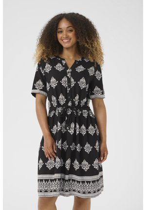 Schwarzes Kleid mit weißem Blumenmuster, kurzen Ärmeln, V-Ausschnitt, Knopfverschluss vorne, Kordelzug in der Taille und dekorativen Akzenten an den Ärmeln und dem Saum.