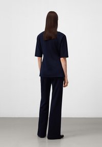 Granatowy dwuczęściowy zestaw składający się z bluzki z krótkim rękawem i spodni z szerokimi nogawkami, wykonany z teksturowanej tkaniny. Prosty design, minimalne detale.