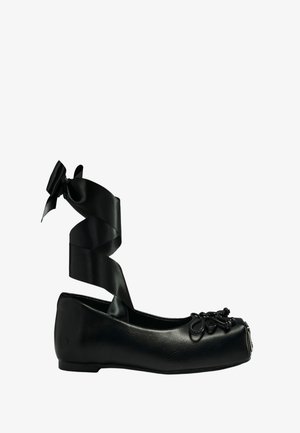 Zwarte ballerina met vierkante neus, decoratieve strik en kralen aan de voorkant, en een lange satijnen enkelstrik.