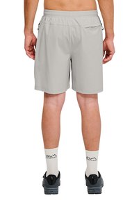 Lichtgrijze shorts met een elastische tailleband, voorzien van zijzakken en een gestructureerde stof. Gemaakt in combinatie met witte sokken en zwarte schoenen.