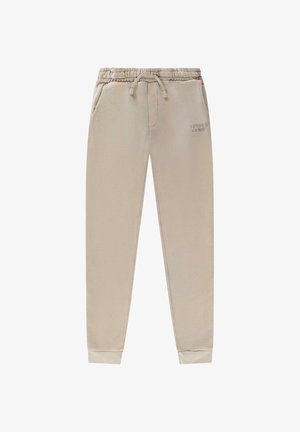 Lichtbeige joggingbroek gemaakt van zacht materiaal, met een elastische tailleband met trekkoord, zijzakken en geribbelde boorden.
