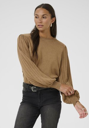 Pull marron côtelé avec des manches ballon, encolure ronde et tissu texturé, associé à un jean noir taille haute et une ceinture noire.