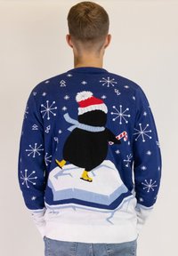 Blauer gestrickter Pullover mit einem Pinguin, der einen roten Hut und einen Schal trägt, der auf Eis steht, umgeben von weißen Schneeflocken. Der Pullover hat einen gerippten Saum.