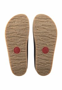 Black footwear soles with textured brown rubber, featuring a red circular logo at the center. Flattened oval shape with a natural appearance.