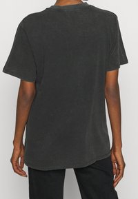 Svart, kortärmad t-shirt gjord av mjukt, texturerat tyg. Har en rund halsringning och en avslappnad passform med en något längre rygg.