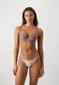 Sutien cu un design structurat în nuanțe de mauve estompat, cu detalii din dantelă și bretele ajustabile. Însoțit de un thong minimalist potrivit.