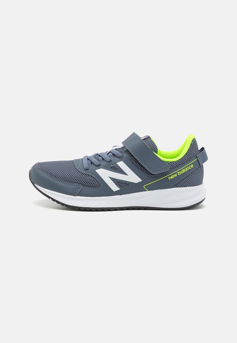 Gray athletic shoe with a mesh upper, white logo, neon green accents, and Velcro strap. Features a cushioned white sole and textured black rubber outsole.