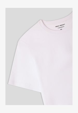 T-shirt bianco pesante in cotone con colletto rotondo e maniche corte, caratterizzato da una superficie liscia e un'etichetta stampata all'interno del colletto.