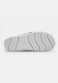 Tălpica sneaker-ului alb cu caneluri de flexibilitate, având detalii de marcă embossate. Material din cauciuc neted cu o suprafață texturată uniform.