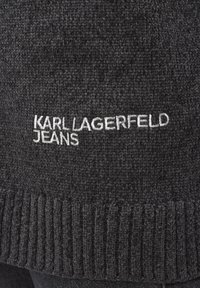 Tmavě šedý pletený svetr s žebrovaným lemem, na přední straně s bílým vyšívaným logem "KARL LAGERFELD JEANS". Měkká textura, ležérní design.