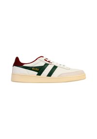 Witte lage sneaker met groene strepen, rode hiel en kraag, beige zool en gouden "Gola" logo aan de zijkant.