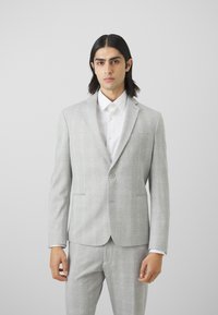Ljusgrå blazer med rutmönster, enkel knappstängning, notch-krage och två framfickor. Kombinerad med matchande byxor.