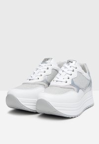 Sneaker bianche con pannello in rete argentata, tomaia testurizzata e suola a piattaforma. Presentano accenti metallici e allacciatura tradizionale.