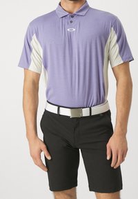 Polo court violet à manches courtes avec des boutons noirs et des accents blancs. Assorti à un short noir et une ceinture blanche avec une boucle en argent.