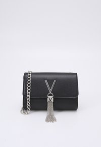 Black textured handbag with a flap closure, silver chain strap, and a decorative tassel. Features a prominent metallic logo accent.