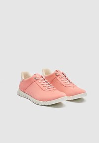 Ζευγάρι ροζ αθλητικά παπούτσια χαμηλού ύψους με λευκές σόλες και κορδόνια, τοποθετημένα διαγώνια προς τα δεξιά σε απλό ανοιχτό γκρι φόντο.