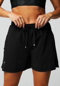 Schwarze Sportshorts mit elastischem Bund, verstellbarem Kordelzug, seitlichen Taschen und einer leicht lockeren Passform. Sauberer, glatter Stoff.