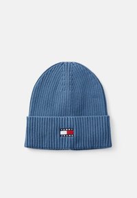 Plavi rebrasti pleteni šešir s preklopom koji sadrži pravokutnu oznaku Tommy Jeans u crvenoj, bijeloj i mornarskoplavoj boji.