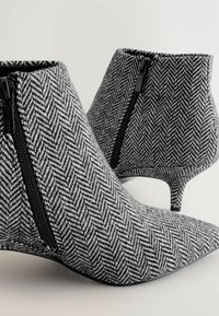 Strukturerede sorte og hvide herringbone ankelstøvler med spids tå, der har en sideskift og en smal stilettohæl.