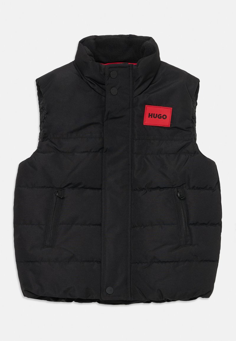 Colete acolchoado preto com gola alta, dois bolsos frontais com fecho éclair e um emblema retangular vermelho com a inscrição "HUGO" na área do peito.