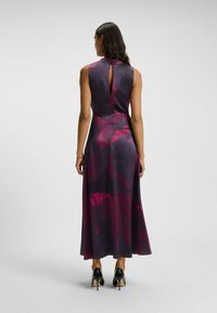 Ampumittainen ilman hihoja oleva mekko syvän purppuran värissä, jossa on suuria kukkakuoseja vaaleanpunaisena ja burgundina. Mekossa on avainreikämäinen selkädesign ja hieman lentävä rakenne.