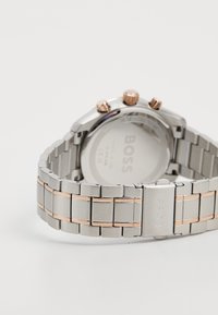 Orologio in acciaio inossidabile con cinturino argento e oro rosa, dotato di tre pulsanti e cassa tonda. Retro incisi con "BOSS."