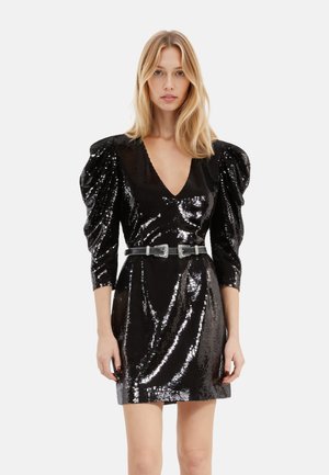 Schwarzes Pailletten-Kleid mit tiefem V-Ausschnitt, Puffärmeln und taillierter Silhouette. Betont mit einem breiten Gürtel mit rechteckiger Schnalle.