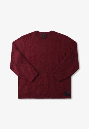 Burgunderfarvet langærmet sweater lavet af blødt, tekstureret stof. Rund hals, afslappet pasform, med en lille sort logopatch ved kanten.