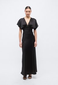 Μαύρο μακρύ φόρεμα από σατέν με βαθύ V-λαιμόκοψη και κοντά φουσκωτά μανίκια, με εφαρμοστή μέση και απαλή, ρέουσα σιλουέτα.