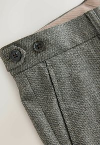 Gray textured fabric pants with two dark buttons at the waistband, featuring a subtle woven pattern and pleats.