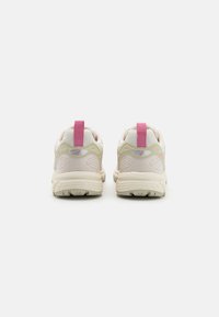 Ljust beige sportskor med rosa detaljer, med en texturerad sula, vadderat krage och en dragflik bak.