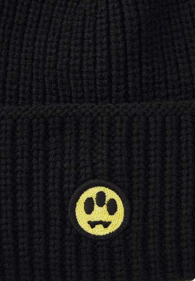 Berretto di maglia nera con trama a costine e un patch rotondo giallo con un design di impronta di zampa nera. Stile semplice e funzionale.