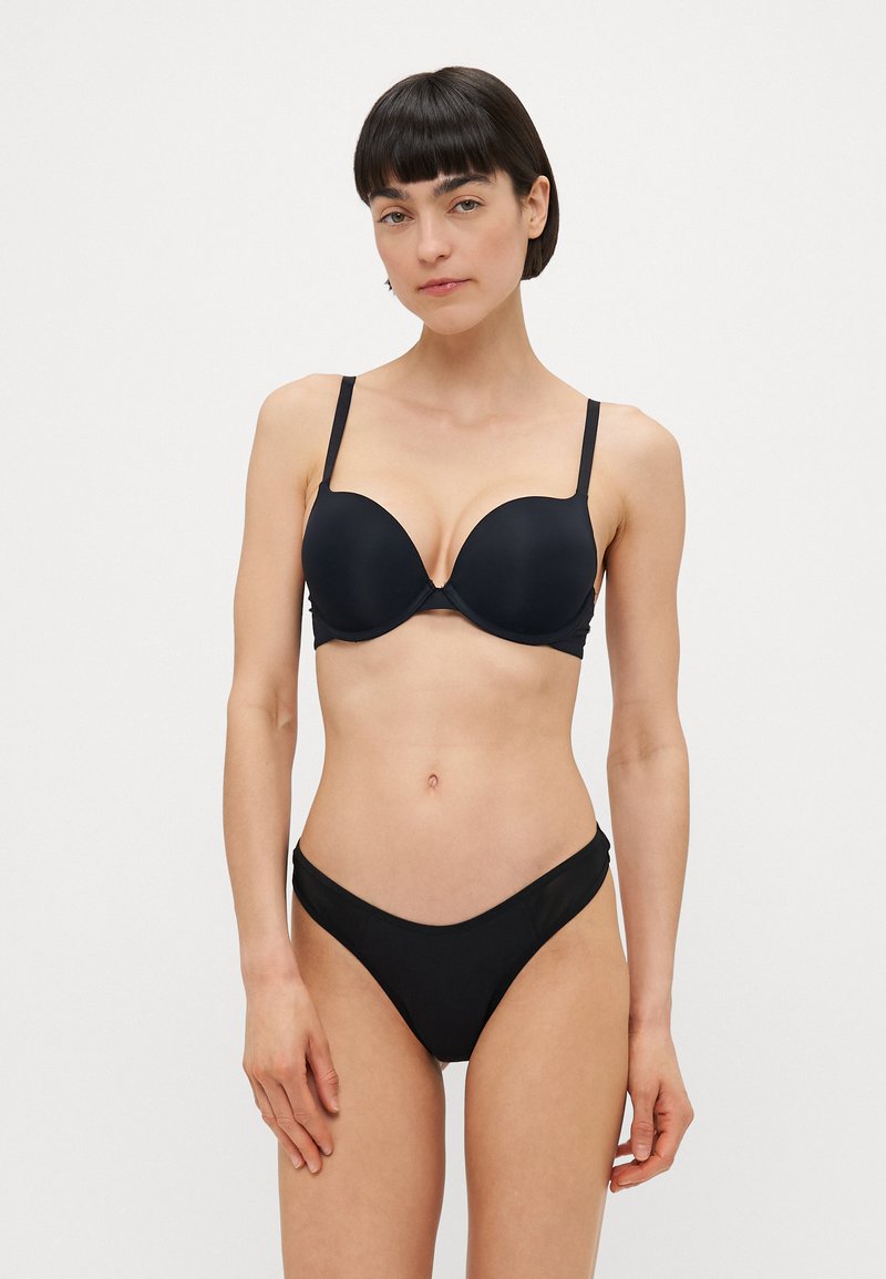 Black push-up bra with smooth fabric, underwire support, and adjustable straps. Matching low-rise bikini bottom with minimal coverage and a curved waistband.