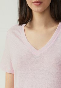 Lichtroze V-hals T-shirt met korte mouwen, gemaakt van een zachte, licht gestructureerde stof. Heeft een eenvoudig ontwerp en zichtbare stikselaccenten.