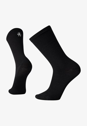 Schwarze Crew-Socken aus glattem Stoff. Mit einem gerippten Bund und einem kleinen, dezenten Logo in der Nähe des Knöchels. Klassisches, vielseitiges Design.