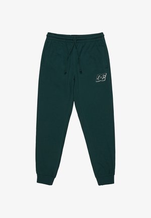 Donkergroene joggingbroek van zacht materiaal, met een elastische tailleband met trekkoord en een klein wit logo op de linker bovenbeen.