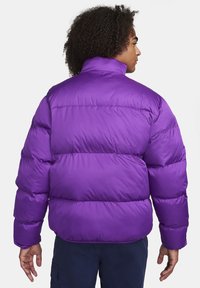 Giacca a vento viola con un alto colletto e cuciture orizzontali. Presenta una consistenza morbida e lucida e una vestibilità ampia e oversize.