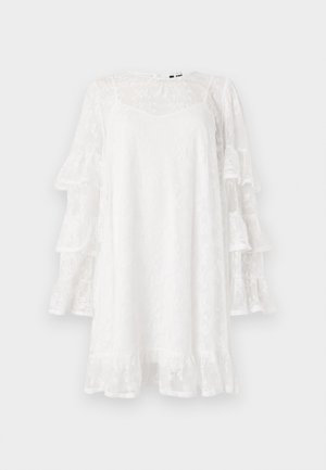 Vestido blanco de encaje con mangas acampanadas, patrón floral y dobladillo con volantes. Diseño ligero, de longitud a la rodilla y con un sutil escote en V.