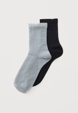 Et par sorte sokker og et par lysegrå sokker med en subtil glitrende tekstur på en hvid baggrund.