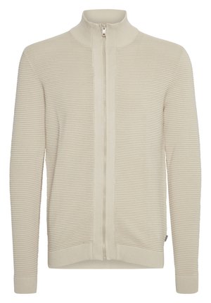 Beige Zip-Up-Pullover mit gerippter Struktur, hohem Kragen und kontrastierendem glattem Einsatz entlang des Reißverschlusses. Strickstoff mit enganliegenden Bündchen und Saum.