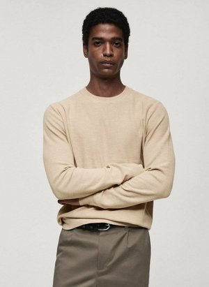 Beige knit long-sleeve shirt with a round neckline, textured fabric, and fitted design, paired with gray trousers and a black belt.