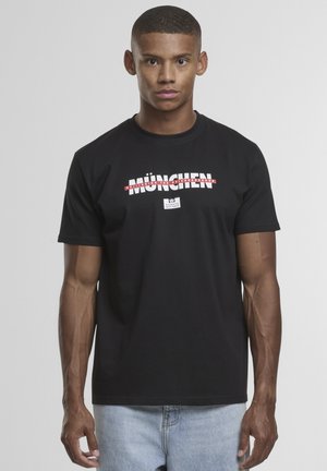 Zwarte katoenen t-shirt met een grafische afbeelding van "MÜNCHEN" in rode en witte tekst. Korte mouwen, ronde hals en een relaxte pasvorm.