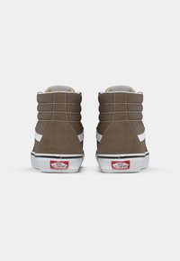 Ruske korkean varren tenkat, joissa on valkoiset sivuviivat, mokkanahkaa, pehmustettu nilkkaosa ja punainen Vans-logo kantapäässä. Valkoinen kumipohja ja ompeluyksityiskohdat.