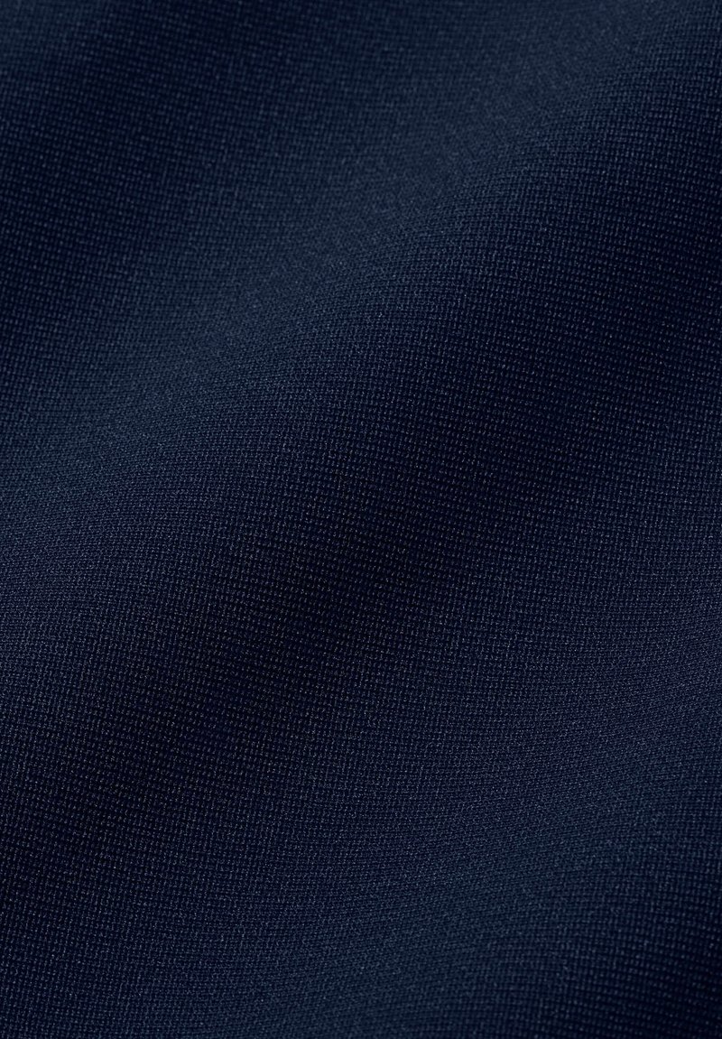 Dunkel marineblauer Stoff mit feiner gewebter Struktur, der leichte Falten und weiches Licht auf der Oberfläche zeigt.