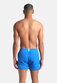 Pantaloni da bagno blu realizzati in tessuto leggero, con vita elastica, una tasca posteriore e un dettaglio di cucitura curata.