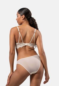 Ivory bralette dengan renda, dilengkapi dengan tali yang dapat disesuaikan dan penutup kait, dipadukan dengan celana dalam transparan ivory yang memiliki aksen renda di tepinya.