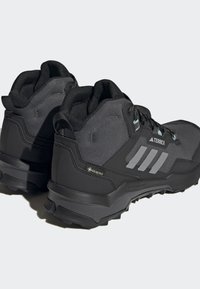 Crne planinarske čizme imaju teksturirani gornji dio od tkanine, gumene potplate s izraženim profilm, te Gore-Tex detalje za vodootpornu zaštitu.